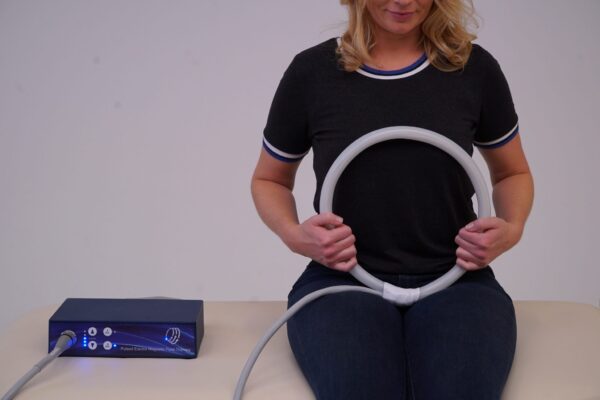 Woman applies loop applicator from TeslaFit Plus 2 to her chest