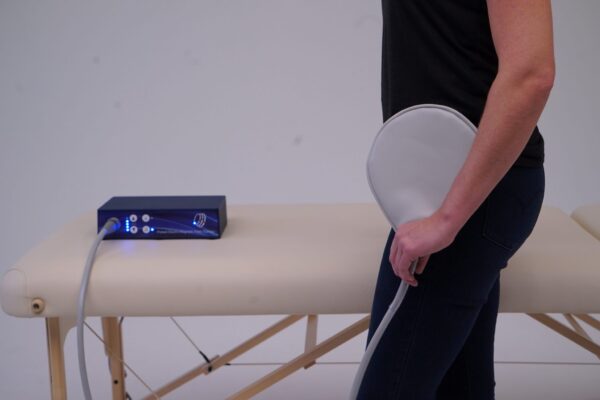 Man Applies Paddle Applicator to his hip from TeslaFit Plus 2 Device