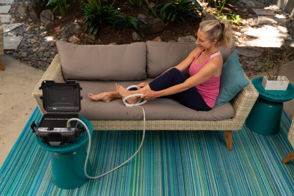 Woman applies butterfly coil to ankle from TeslaFit Plus 2 Portable