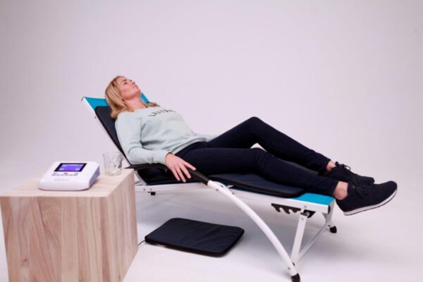 Woman lying in chair on PEMF treatment pad from BioBalance PEMF Device