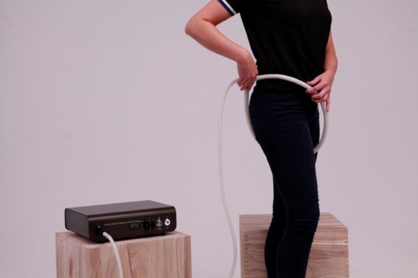 Woman applies Loop applicator from TeslaFit pro around her hip for PEMF Therapy