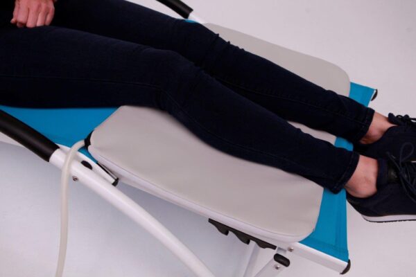 Woman lying on chair with PEMF applicator pad under her calves for PEMF Therapy