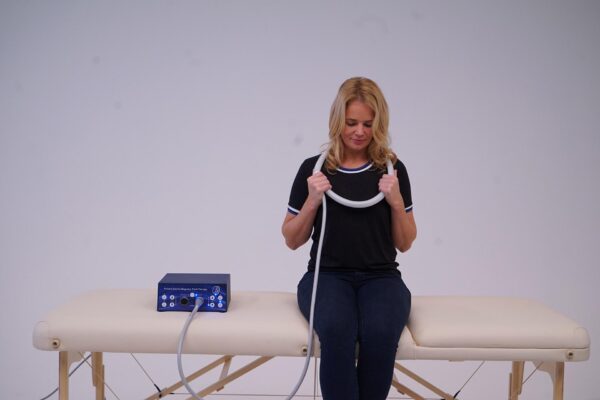 Woman sits and puts loop applicator around her neck for PEMF Therapy