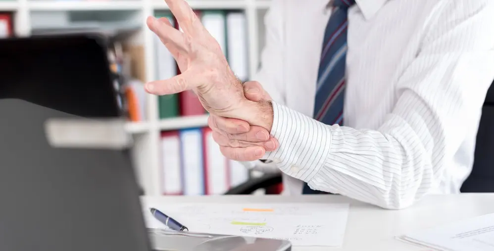 Man at work holding wrist in pain with carpal tunnel syndrome