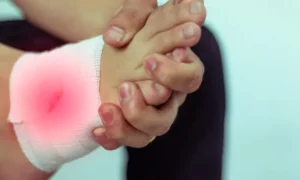 Person holding their foot with a red inflamed infection on top of foot