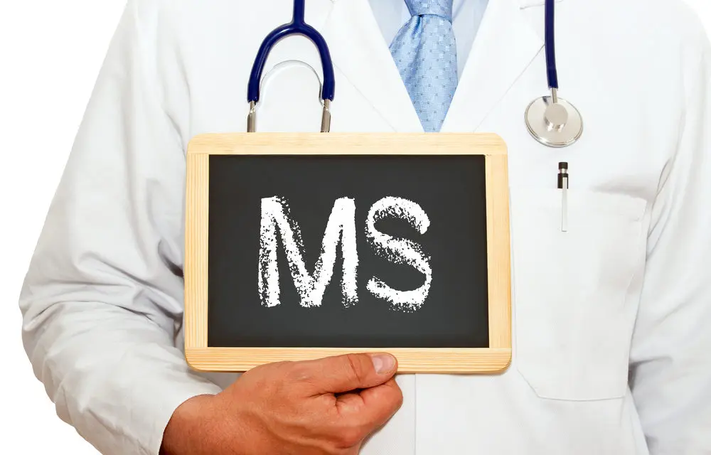 Doctor holding up a chalk board with "MS" written on it