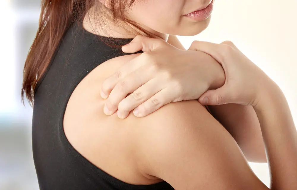 Women rubs her shoulder in pain