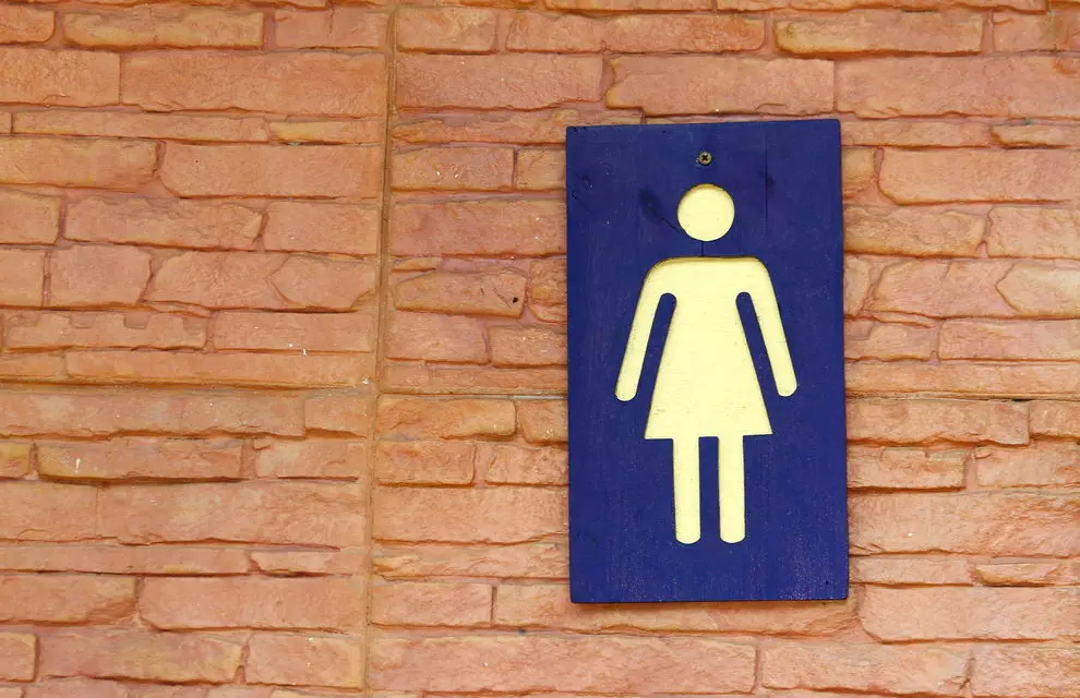 Blue Women's Bathroom sign on brick wall